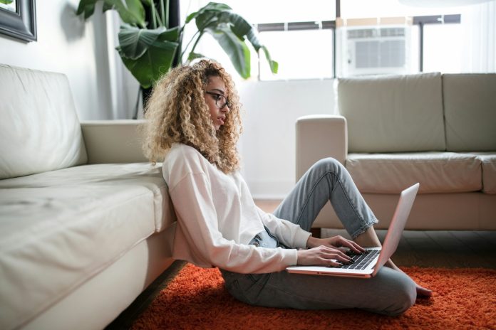 Photo by Thought Catalog woman sitting on floor and leaning on couch using laptop